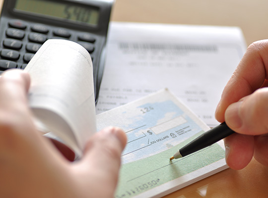 Customer writing check and reviewing checkbook for reorder